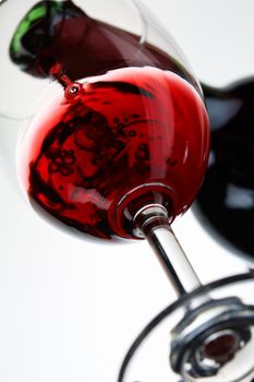 Red wine pour in a glass on white background