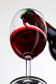 Red wine pour in a glass on white background