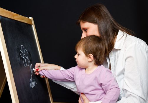 Mother and little daughter writing on a blackboard