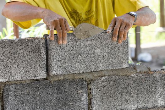 Bricklayer putting down another row of bricks in site