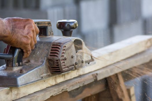 Carpenter working with electric planer  in his workshop, close up on the tool with hands
