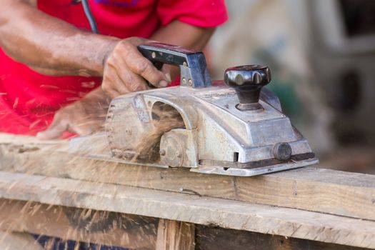 Carpenter working with electric planer  in his workshop, close up on the tool with hands