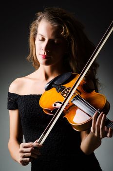 Woman with violin in dark room
