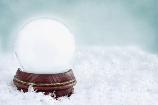 Blank snow globe with with copy space available against a blue background.