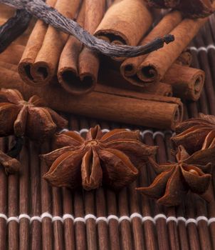 Aroma Spicy with Cinnamon Sticks, Anise Star and Vanilla Pods closeup on Straw mat background