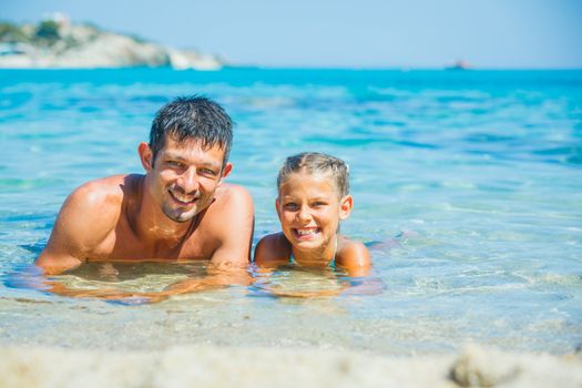 Father and cute daughter playing and swimming in the transparent sea