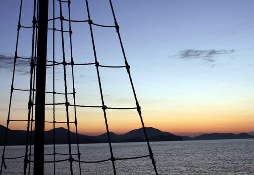 rigging of boat over landscape before sunrise