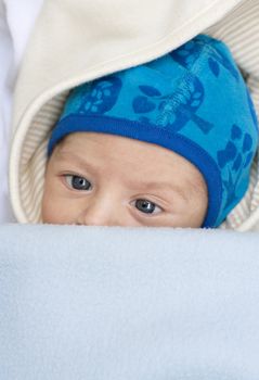 Close up of infant with a cute little blue hat, squinting, crosseyed, funny face