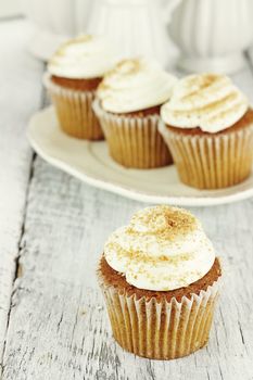 Pumpkin spice cupcakes frosted with cream cheese icing and sprinkled with brown sugar. Shallow depth of field.