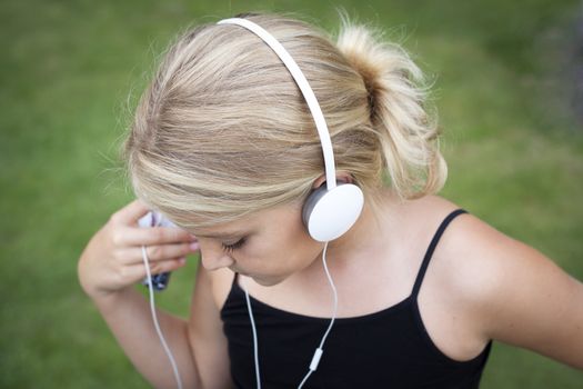 Child with headset listening to music on her smartphone. Short depth of field