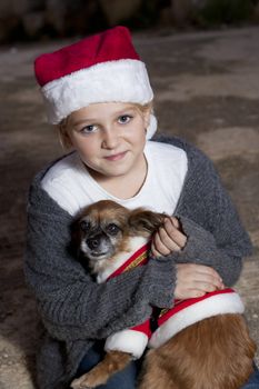 Girl dressed in christmas hat holding a dog with christmas costume