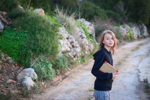 Girl carrying books, walking in the countryside