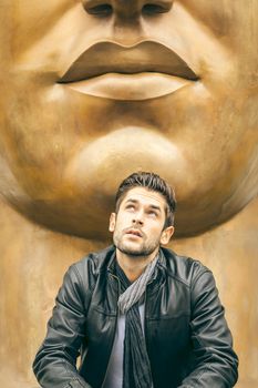An image of a young man and a big mouth statue