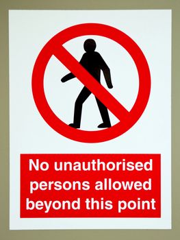 no unauthorised persons allowed beyond this point sign on a gray wall