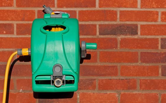 garden hose reel kit installed on a brick wall (copy-space available)