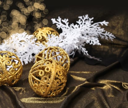 Golden Christmas balls on shiny fabric and white decoration branch