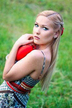 blonde girl holding a heart in the park 