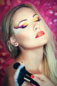 Close up portrait of a blonde girl holding brushes 