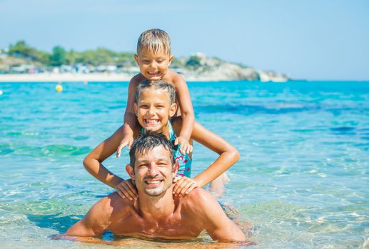 Family - father with his kids have fun and swimming in the transparent sea