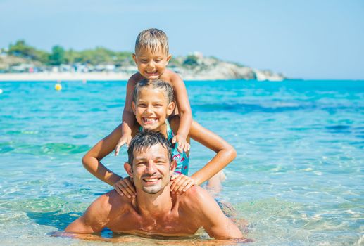 Family - father with his kids have fun and swimming in the transparent sea