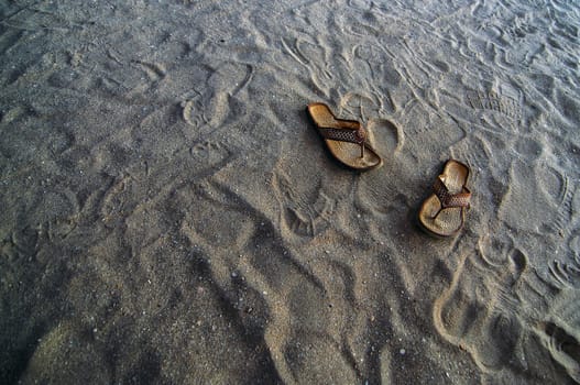 Flip flops in the sand at a beach.