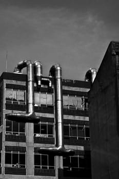 A black and white shot of pipes running down the side of a building.