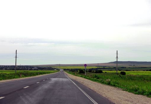 Wide highway and green meadow. The summer travel