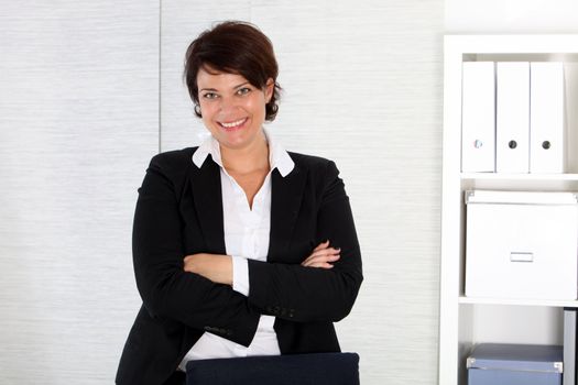 Happy brunette businesswoman standing in a pristine office