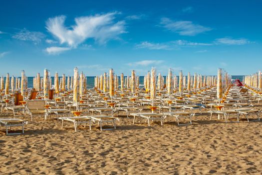 withdrawn yellow umbrellas and sunlongers on the sandy beach in Italy