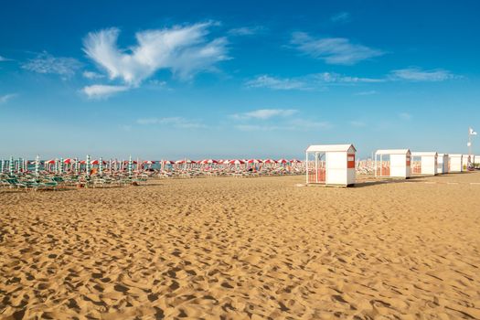 red and white umbrellas and sunlongers on the sandy beach in Italy