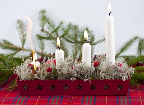 Burning candles in a advent candle wreath setting fire