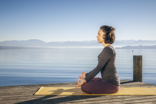 An image of a pretty woman doing yoga at the lake