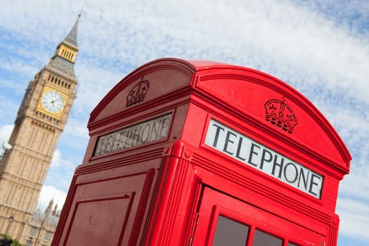 Main London symbols: red public telephone box and clock on Big Ben tower of Westminster Palace on cloudy sky background in Great Britain