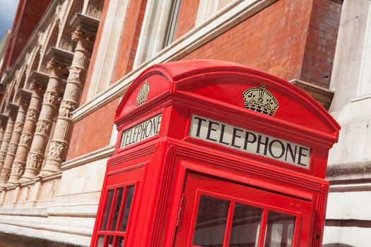 Traditional London symbol red public phone box on building facade background, Great Britain