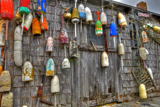 Series of lobster buoys hanging on the side of a boathouse