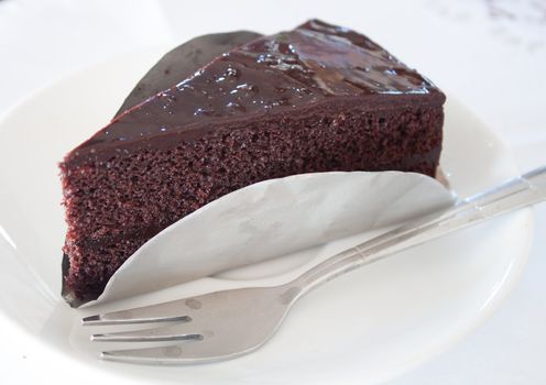 A piece of dark chocolate cake on white isolated background