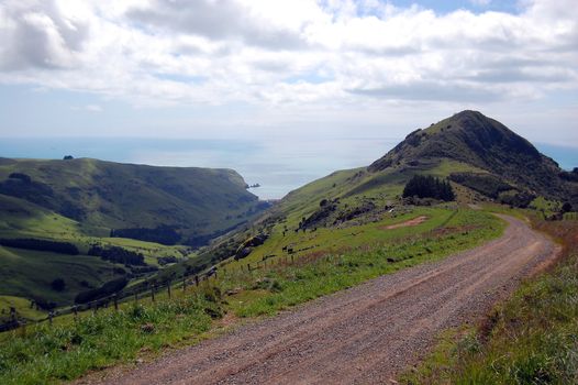Gravel road goes downhill to rural valley, Banks Peninsula, New Zealand