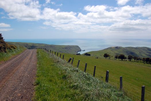 Gravel road goes downhill to rural valley, Banks Peninsula, New Zealand