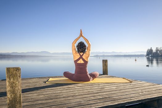 An image of a pretty woman doing yoga at the lake