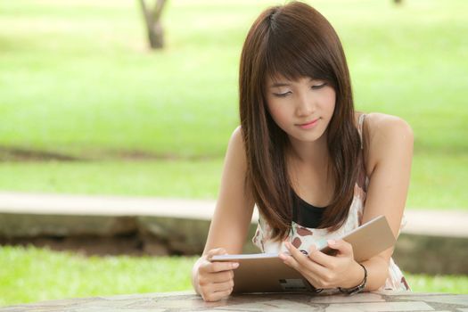 Beautiful asian girl reading her text in notebook at park outdoor