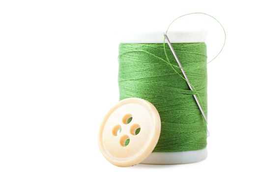 Single spool with green thread with needle and button