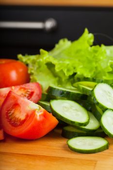 Vegetables (tomato, cucumber, salad) on a wooden table