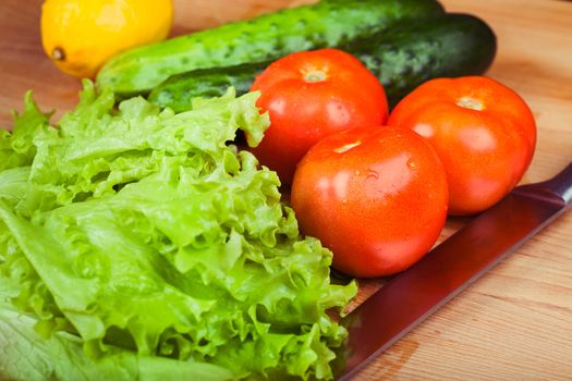 Vegetables (tomato, cucumber, salad) on a wooden table