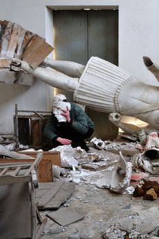 Obscured figure among ruins broken statues and debris in post apocalyptic setting.