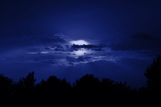 Full moon obscured by clouds. Night sky moonlight nature background.