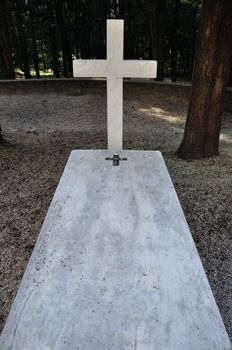 Cross and marble grave tombstone among trees.