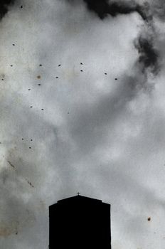 Church cross silhouette, overcast sky and flying birds on stained grungy paper. Orthodox monastery at Meteora, Greece.