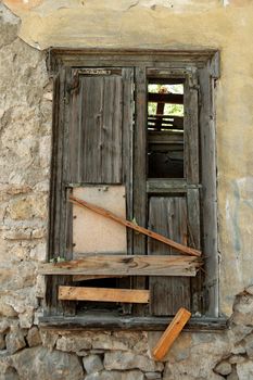 Boarded up old window shutter and crumbling wall of abandoned house.
