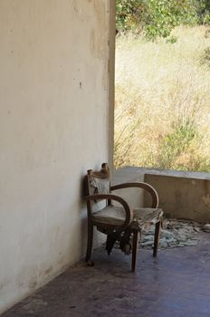 Old armchair and broken glass on the porch of an abandoned rural house.