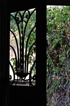 Open door with vintage metalwork motif in dark abandoned house.